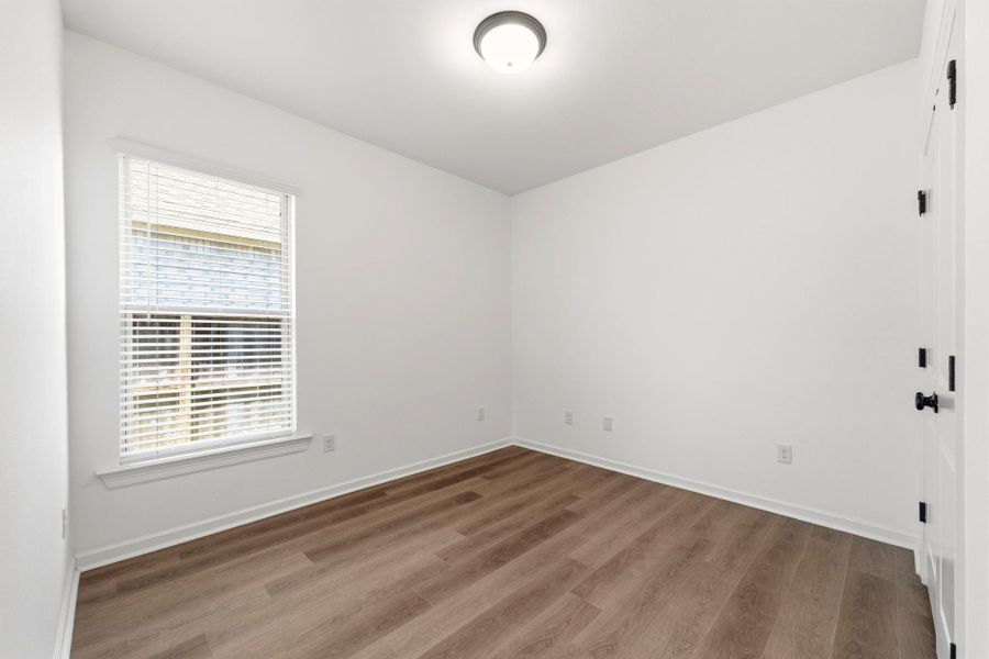 Well-sized secondary bedroom with modern finishes and luxury vinyl plank flooring.