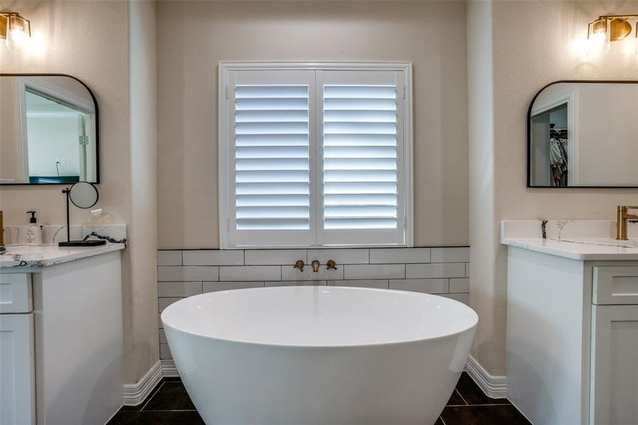 Bathroom featuring tile patterned floors, a tub to relax in, and vanity