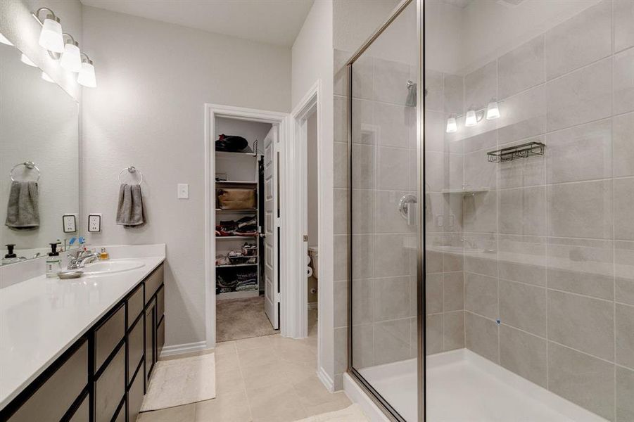 Bathroom with tile patterned floors, a shower with shower door, and vanity