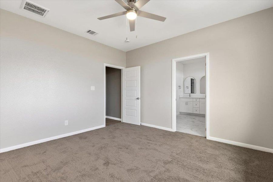 Primary bedroom with soft carpet flooring and an adjacent private bathroom. Primary bedroom with soft carpet flooring and an adjacent private bathroom.