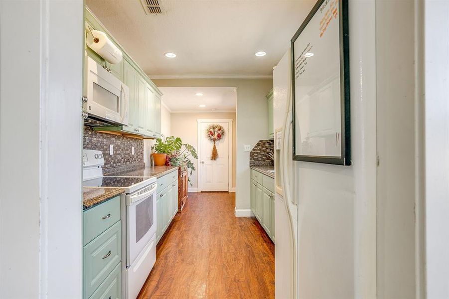 Kitchen featuring green cabinets, white appliances, light wood-style flooring, recessed lighting, and crown molding
