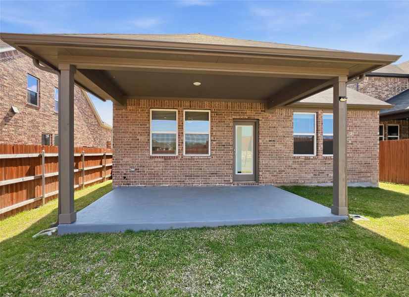 Rear view of house with a fenced backyard, a patio area, and brick siding