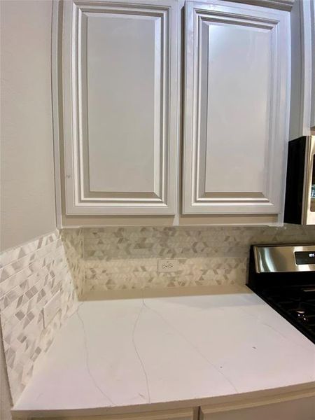 Close up of White raised panel cabinets, decorative mosaic tile kitchen backsplash, and Calacatta Lincoln Quartz counters Close up of White raised panel cabinets, decorative mosaic tile kitchen backsplash, and Calacatta Lincoln Quartz counters