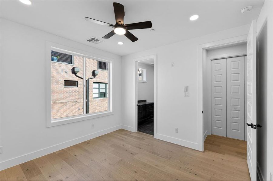 Unfurnished bedroom featuring light wood-style flooring, ensuite bath, a ceiling fan, and recessed lighting