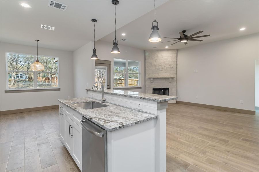 Kitchen island with pendant lighting over sink and dishwasher with breakfast bar