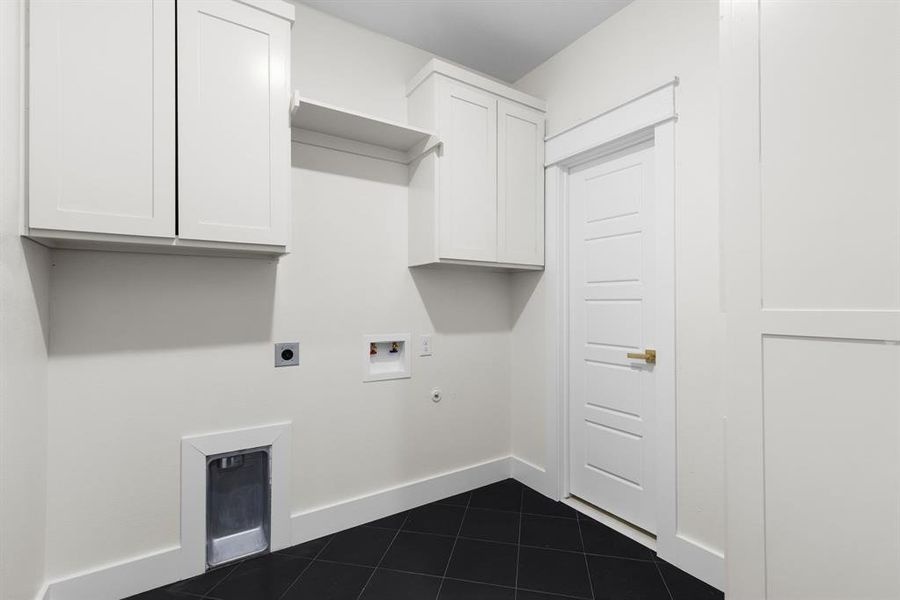 Washroom with washer hookup, hookup for an electric dryer, dark tile patterned flooring, and cabinets