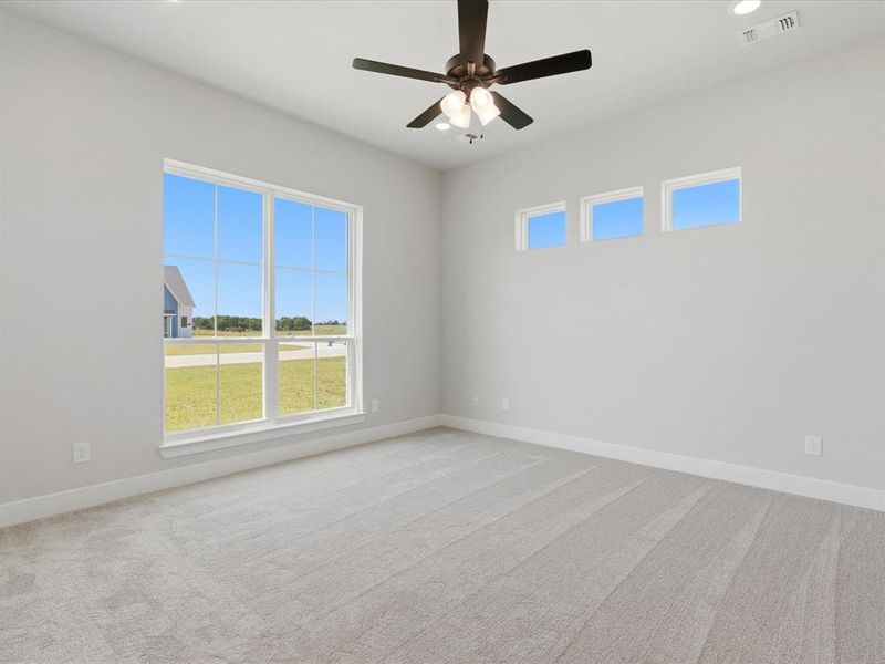 Spacious interior featuring a large picture window, three transom windows, light-colored carpeting, a ceiling fan with integrated lighting, and recessed ceiling lights