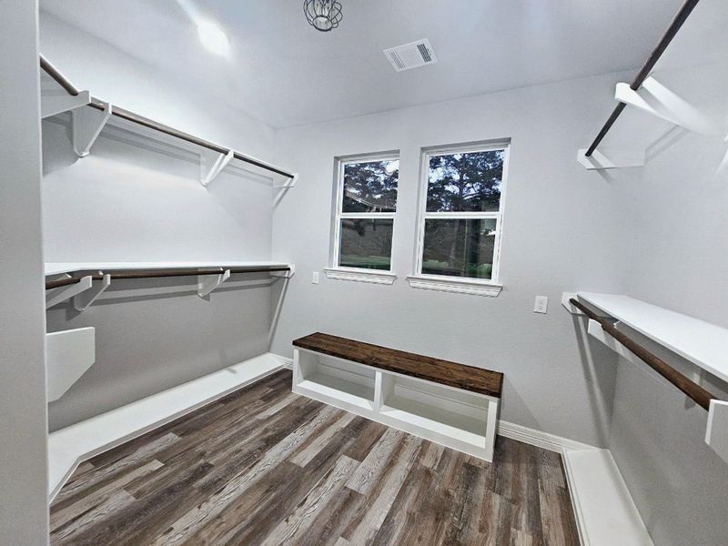 Featuring ample hanging space, built-in shelving, and a wooden bench.