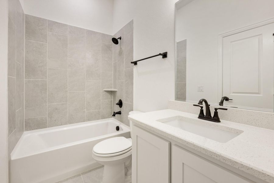 Bathroom with gray tile tub-shower combo, white vanity with quartz countertop, and black fixtures Bathroom with gray tile tub-shower combo, white vanity with quartz countertop, and black fixtures