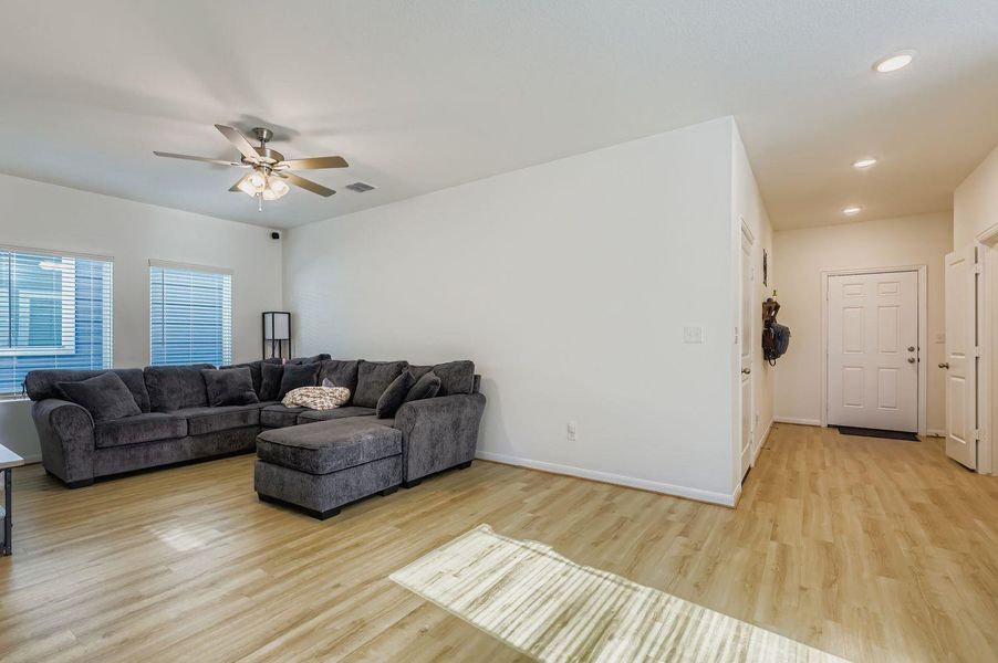 Living area with light wood-style floors, a ceiling fan, and recessed lighting