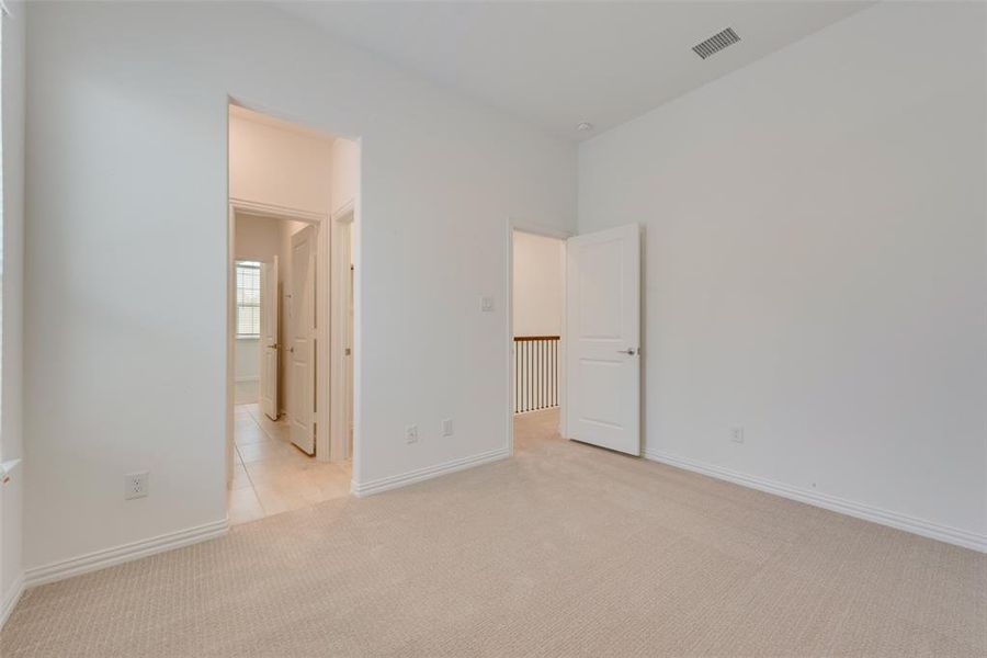 Unfurnished bedroom with ensuite bath and light colored carpet