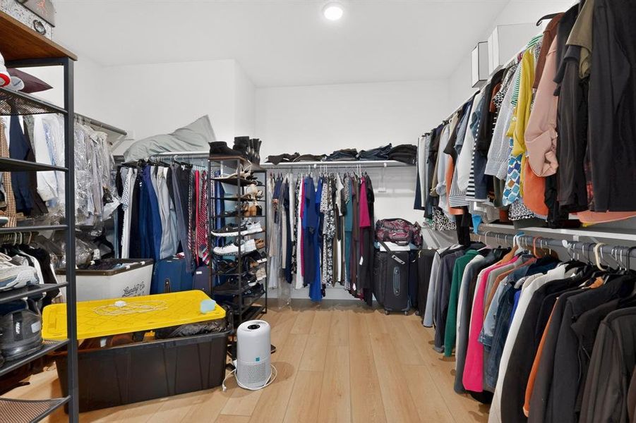 Spacious walk-in closet featuring light wood-finish flooring and extensive shelving Spacious walk-in closet featuring light wood-finish flooring and extensive shelving