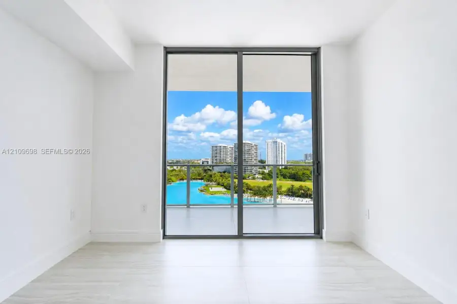 Floor-to-ceiling sliding glass door providing access to a covered balcony with a glass railing