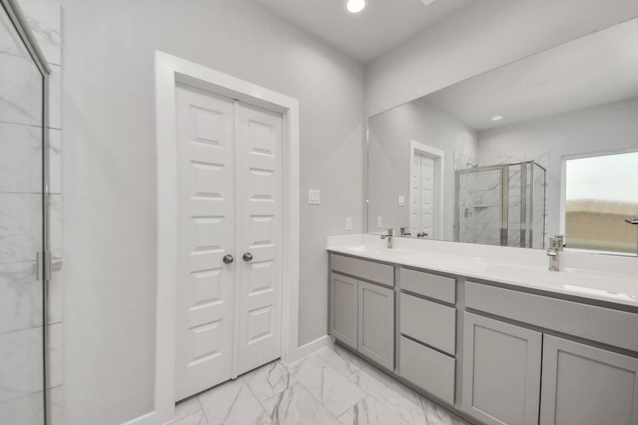 Elevate your dailyroutine at the elegant vanity, now equipped with double sinks, lightcountertops, modern hardware, and beautiful recessed lights.