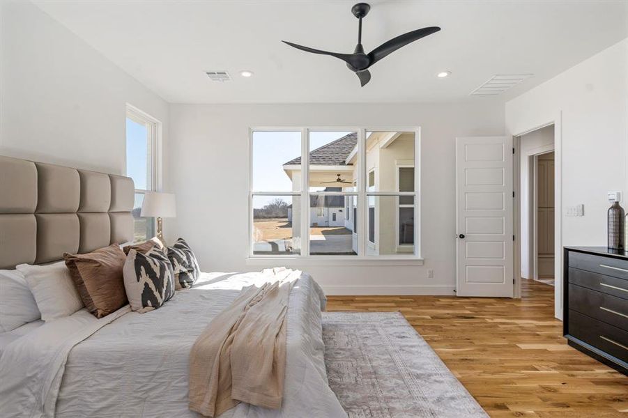 Bedroom featuring ceiling fan, multiple windows, and light wood-type flooring