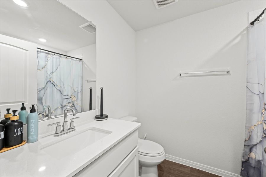 A pristine bathroom features a crisp white vanity and a shower area with a contemporary curtain.