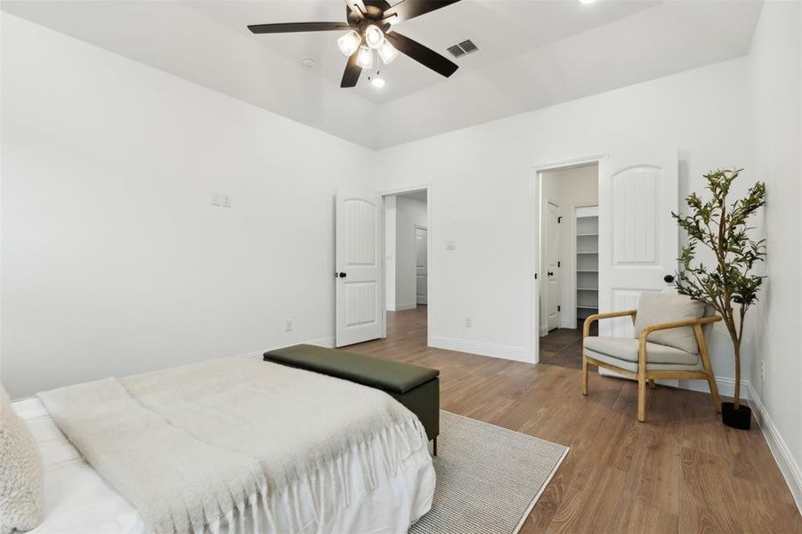 Bedroom with a walk in closet, hardwood / wood-style flooring, and ceiling fan