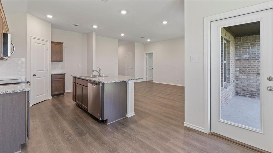 Open concept living space featuring a central kitchen island with a double basin sink and stainless steel appliances