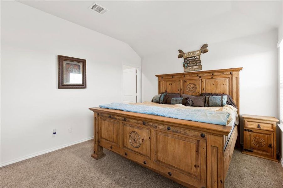 Bedroom featuring dark colored carpet and vaulted ceiling Bedroom featuring dark colored carpet and vaulted ceiling