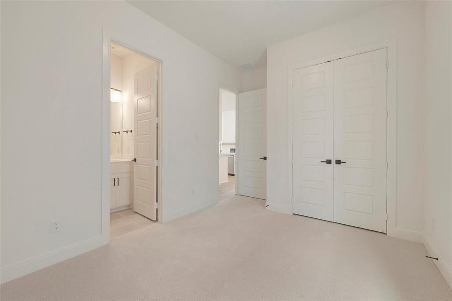 Carpeted room featuring white walls, white baseboards, and a double-door closet with matte black hardware
