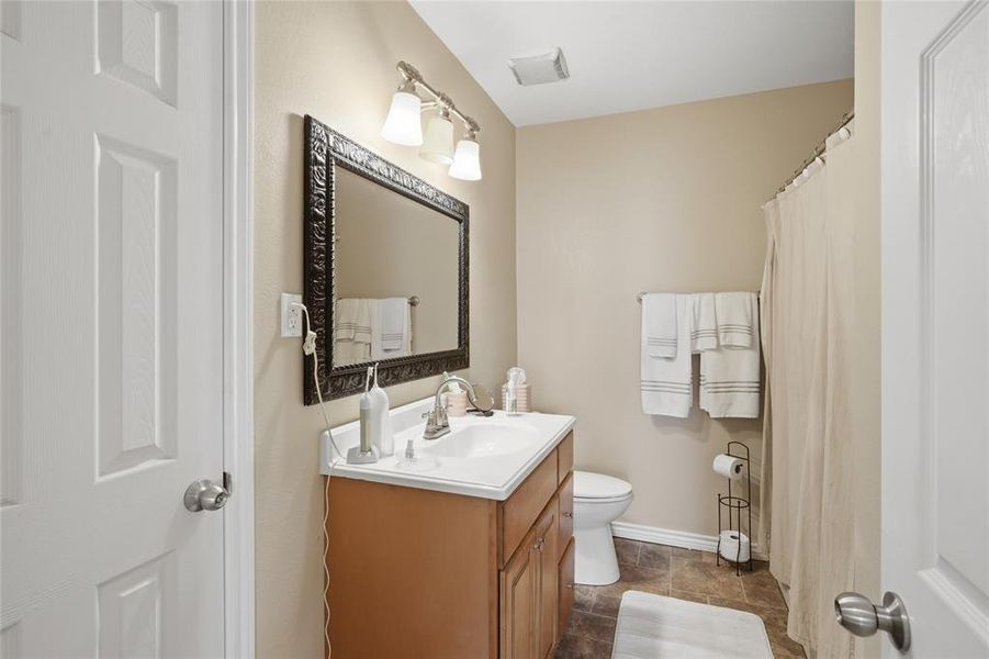 Bathroom featuring a single vanity with an integrated sink, a large framed mirror, and a three-light fixture
