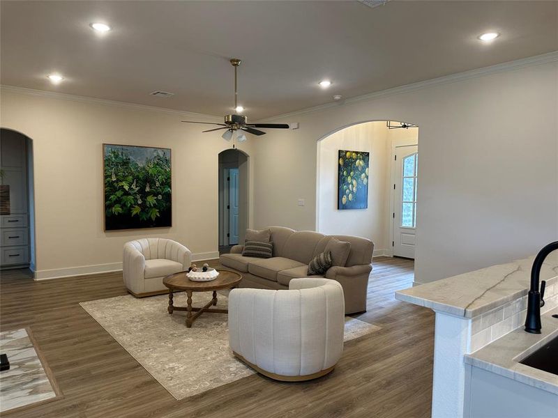 Spacious living area featuring wood-finish flooring, recessed lighting, and crown molding