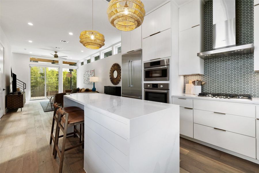 Kitchen with a kitchen island, a ceiling fan, light stone countertops, a breakfast bar, and white cabinets