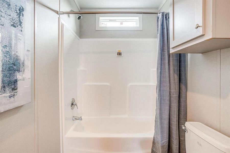 Bathroom with shower / tub combo and toilet