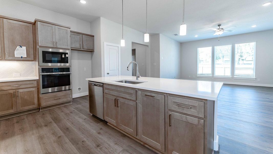 Kitchen featuring appliances with stainless steel finishes, hanging light fixtures, light wood-type flooring, recessed lighting, and light stone countertops Kitchen featuring appliances with stainless steel finishes, hanging light fixtures, light wood-type flooring, recessed lighting, and light stone countertops