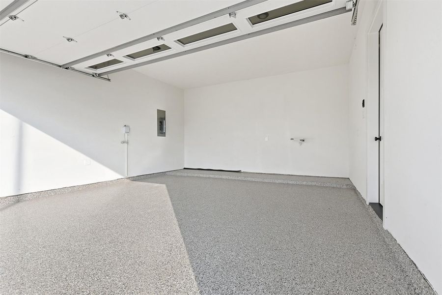 The two-car garage is finished with a durable epoxy-coated floor and includes a modern glass-panel overhead door.