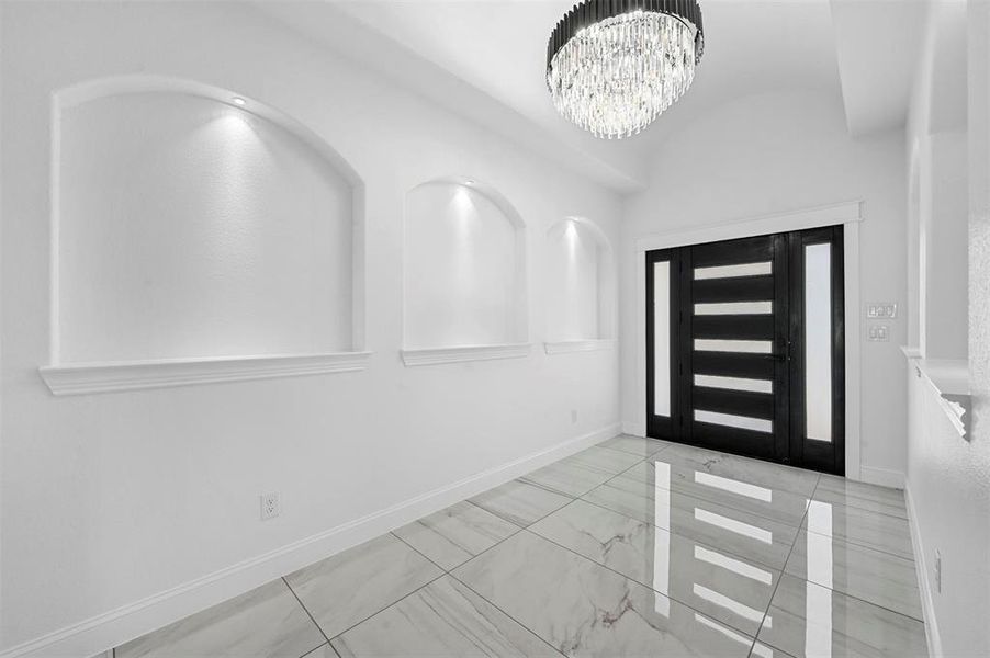 Tiled entryway featuring a notable chandelier