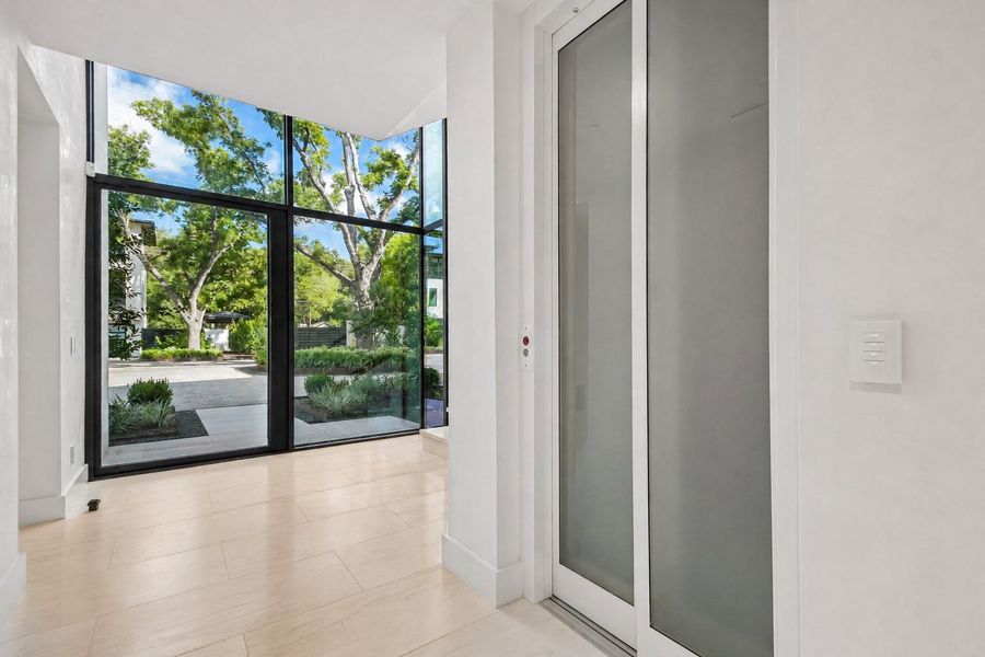 Towering floor-to-ceiling windows flood the modern entryway with light and frame lush outdoor views. Towering floor-to-ceiling windows flood the modern entryway with light and frame lush outdoor views.