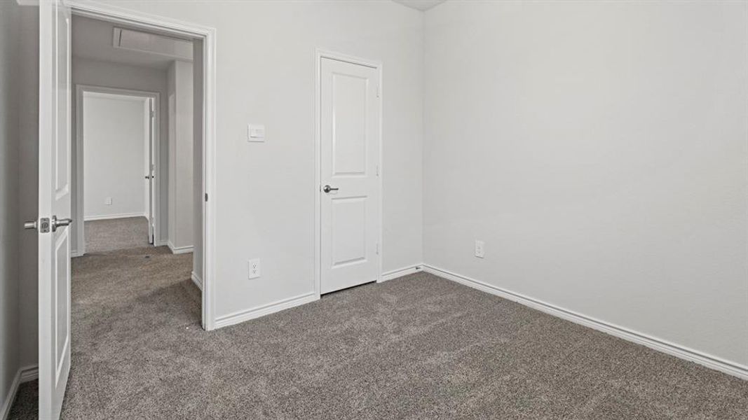 Unfurnished bedroom with dark colored carpet and baseboards