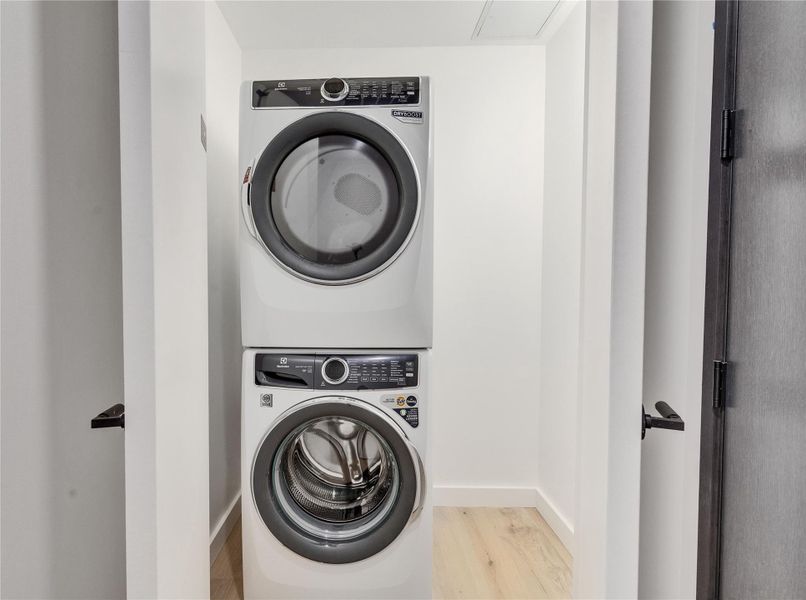 Modern stacked laundry units fit seamlessly into a dedicated closet with light wood flooring. Modern stacked laundry units fit seamlessly into a dedicated closet with light wood flooring.