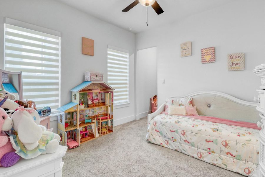 Secondary bedroom on the first floor features plush carpeting, ceiling fan, two large windows, and a full ensuite bathroom. There is also a fun hideaway space through that passageway for storage, toys, or imagination.