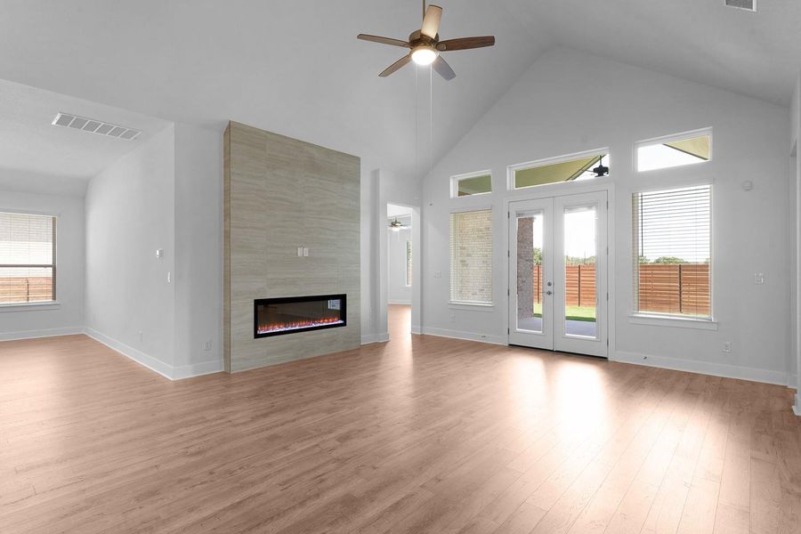 A grand living space welcomes with soaring vaulted ceilings, a sleek linear fireplace, and direct backyard access.