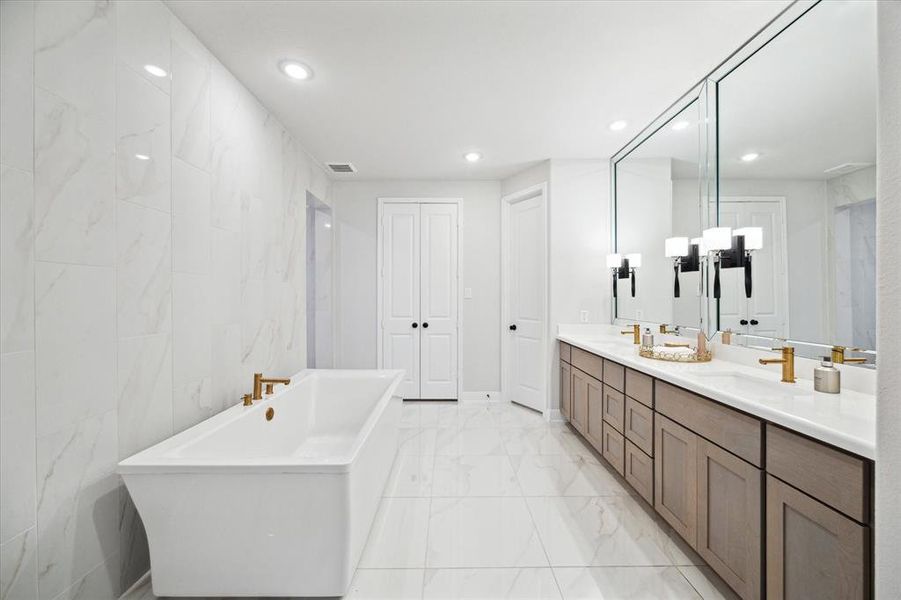 Stunning primary ensuite bathroom attached to the 1st primary bedroom features a floor to ceiling gala smooth silk polished tile, Oversized Kohler freestanding tub with its own 40 gallon water heater.