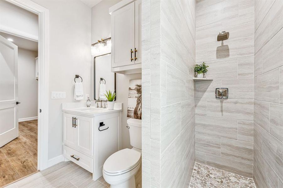 Bathroom featuring wood-type flooring, toilet, vanity, and a tile shower