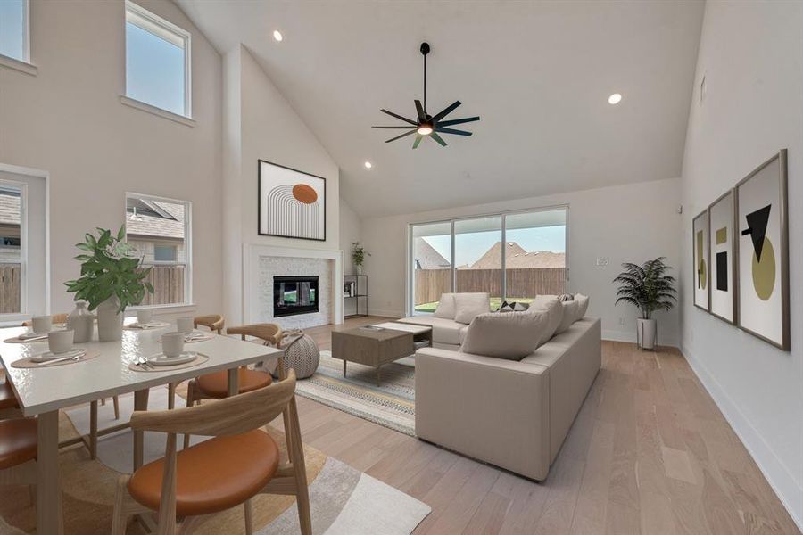 Living room featuring high vaulted ceiling, recessed lighting, a glass covered fireplace, light wood-type flooring, and ceiling fan Living room featuring high vaulted ceiling, recessed lighting, a glass covered fireplace, light wood-type flooring, and ceiling fan