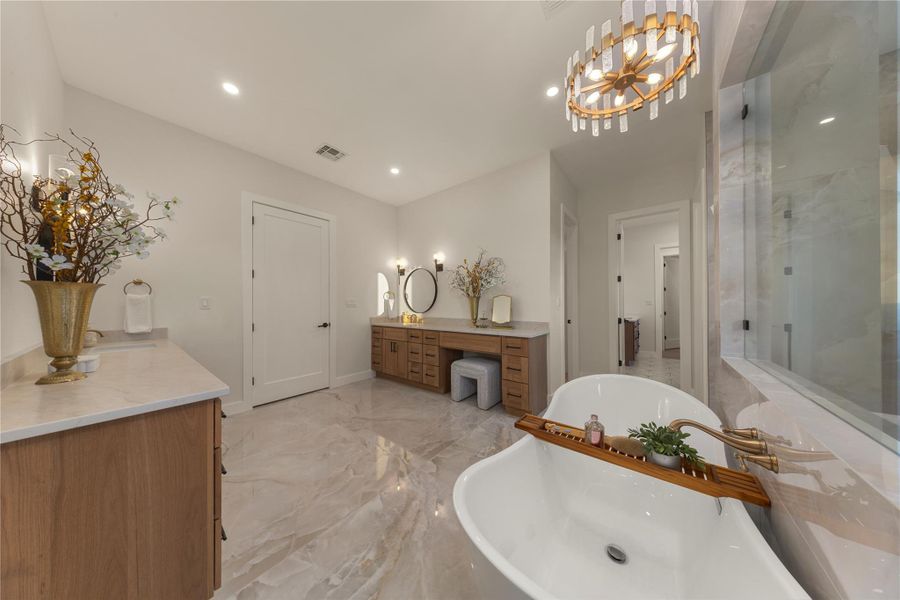 Bathroom with double vanity, a chandelier, light marble finish flooring, a shower stall, and a soaking tub