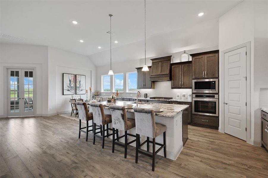 Kitchen with custom exhaust hood, stainless steel appliances, a kitchen breakfast bar, dark wood-type flooring, and vaulted ceiling