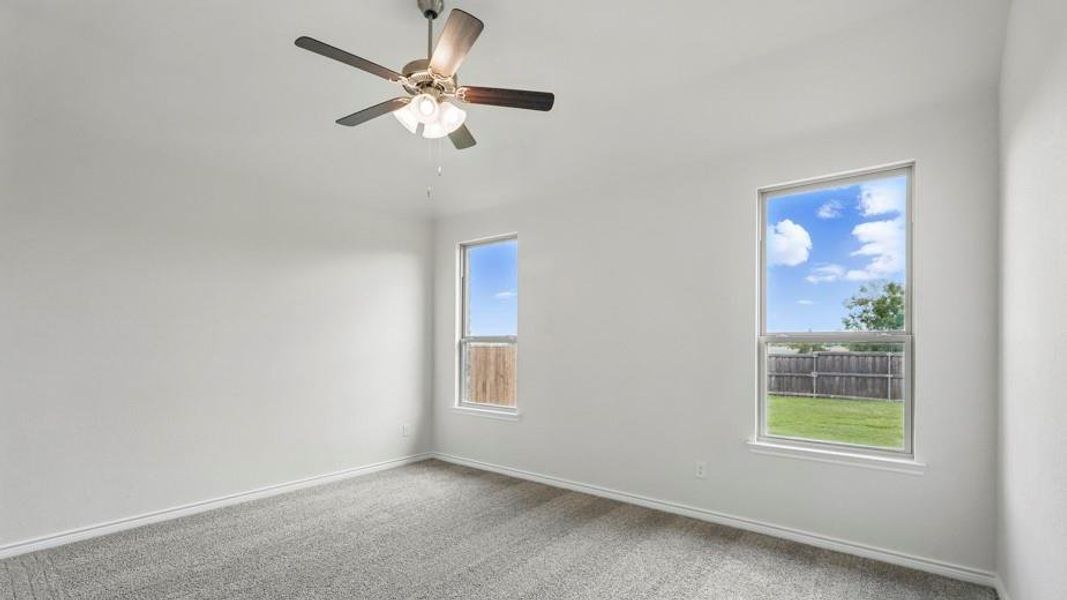 Carpeted spare room featuring a ceiling fan and baseboards