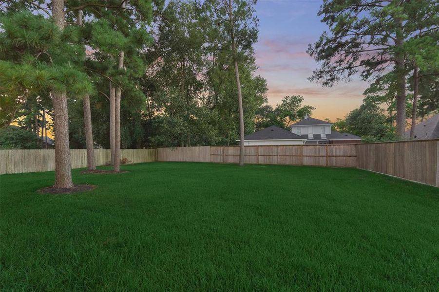 Several existing trees were saved during construction to provide a shaded backyard space. Yard is fenced on all sides.