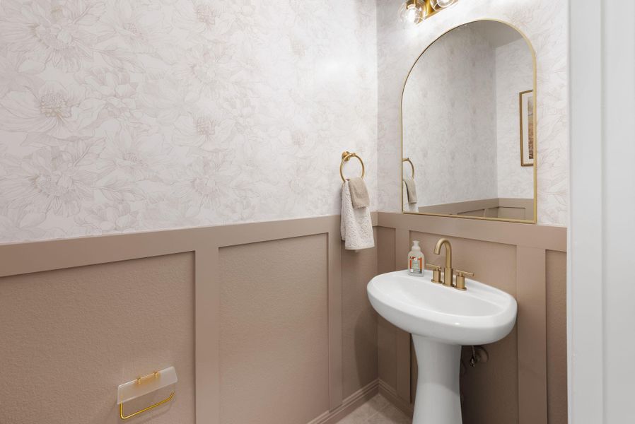 Bathroom with wallpapered walls, a decorative wall, and wainscoting
