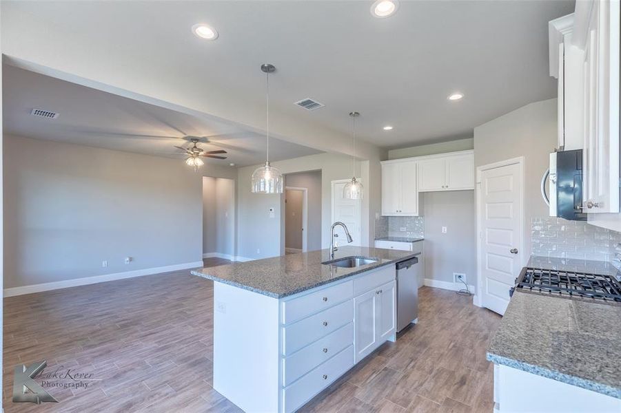 Kitchen featuring dark stone countertops, ceiling fan, white cabinets, wood finished floors, and recessed lighting
