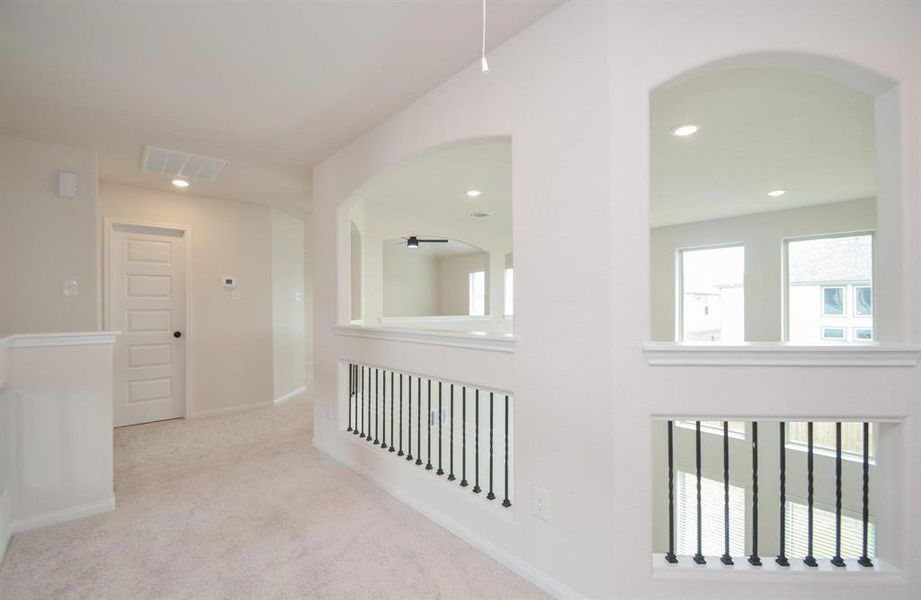 A spacious upstairs landing overlooking the living area, featuring elegant open railings with modern iron spindles. This versatile space provides a seamless connection between the home's levels, enhancing the open-concept feel while maintaining a private, cozy atmosphere.