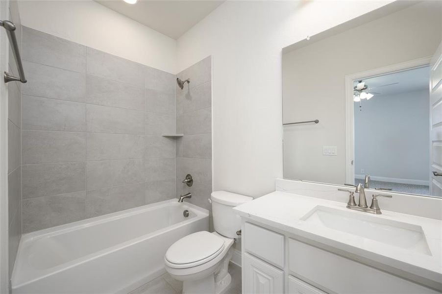 Full bathroom with ceiling fan, tiled shower / bath, vanity, and toilet