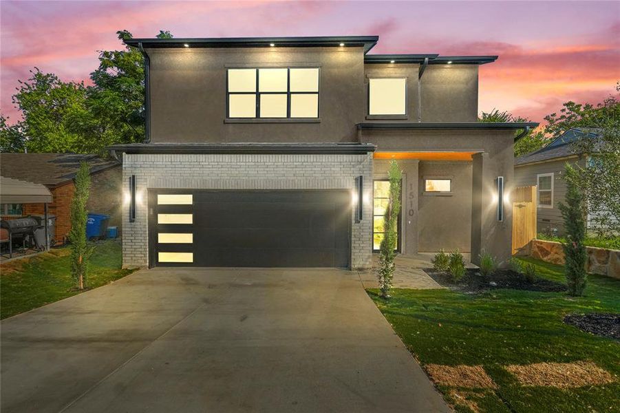 Contemporary house with brick siding, stucco siding, driveway, and an attached garage