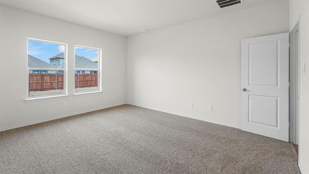 The property features an empty room with grey carpeting, white walls, and two windows providing natural light