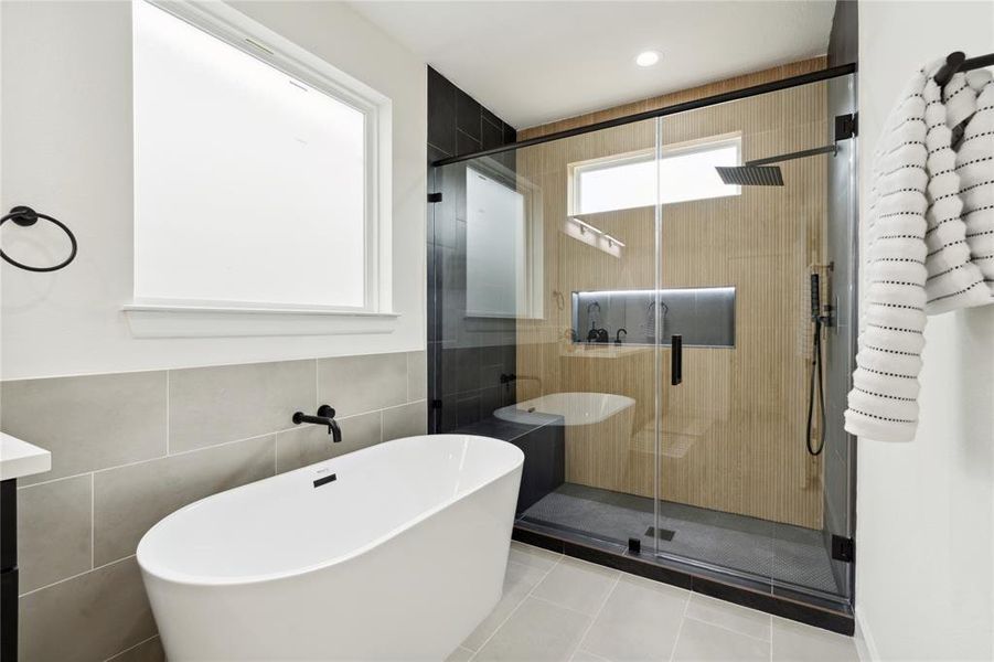 Elegant bathroom featuring a sleek freestanding tub, modern black fixtures, and a spacious glass-enclosed shower with contemporary tile and rainfall showerhead. Elegant bathroom featuring a sleek freestanding tub, modern black fixtures, and a spacious glass-enclosed shower with contemporary tile and rainfall showerhead.